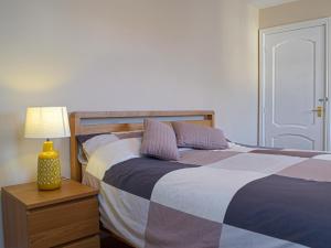 a bedroom with two beds with a lamp on a night stand at Goslings in Marloes +2 photos