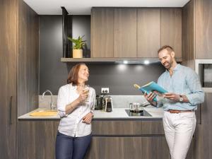 a man and a woman standing in a kitchen at The Sebel Canberra Campbell in Canberra