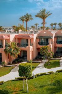 a large pink building with palm trees in the background at Ali Baba Palace Resort - Families and Couples Only in Hurghada