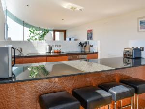 a kitchen with a counter with stools at The Balcony in Westward Ho