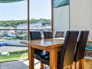 a dining room table with black chairs and a large window at The Balcony in Westward Ho