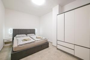 a white bedroom with a bed and a dresser at Gasparevic Apartments in Rovinj