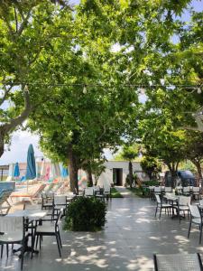 a patio with tables and chairs under trees at Ayvalık Denizyıldızı Otel in Ayvalık
