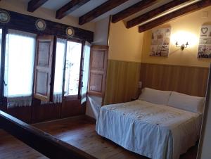 a bedroom with a bed and two windows at Casas Rurales La Casuca in Ojedo