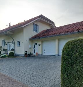 a house with two garage doors and a driveway at Ferienwohnung Gartentraum in Oberzent