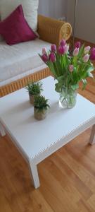 a white coffee table with a vase of flowers on it at Ferienwohnung Gartentraum in Oberzent +20 photos