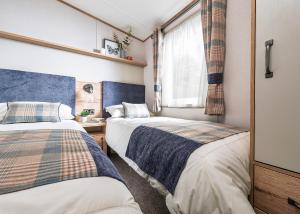 two beds in a small room with a window at Trossachs Holiday Park in Gartmore