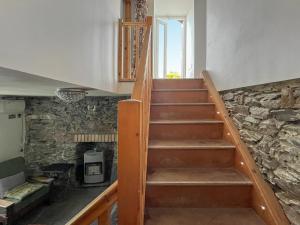a wooden staircase in a room with a stone wall at Fronfanol - Uk49776 in Llanfair Talhaiarn