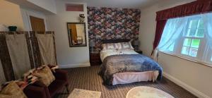 a bedroom with a bed and a chair and a window at Island House in Lanercost