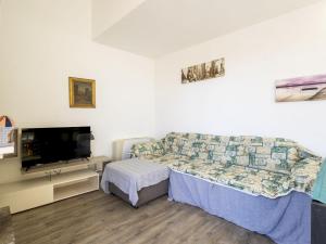 a bedroom with a couch and a tv in it at Apartment Lake & Pool by Interhome in Leggiuno