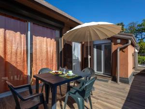 a wooden table with chairs and an umbrella on a deck at Apartment Lake & Pool by Interhome in Leggiuno