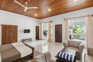 a bedroom with a bed and a couch and a tv at Mihira Gedara Apartments in Unawatuna