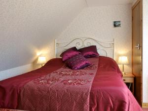 a bedroom with a bed with purple sheets and pillows at Waterfall Cottage in Glendale +1 photo