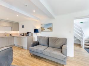 a living room with a couch and a kitchen at Cartmel Cottage in Lindale