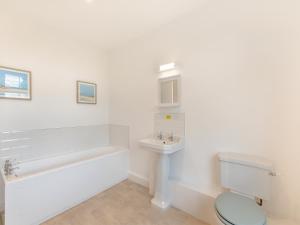 a white bathroom with a tub and a toilet and a sink at Cartmel Cottage in Lindale