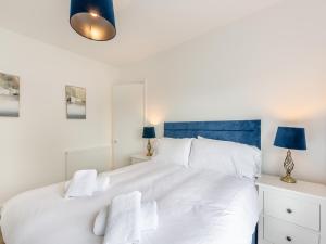 a bedroom with a large white bed with blue accents at Cartmel Cottage in Lindale