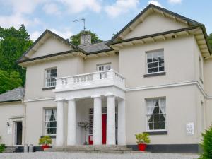 a white house with a red door and columns at Gibson Apt- Cv11 in Liskeard