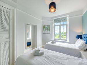two beds in a white room with two windows at Baycliff Apartment in Lindale