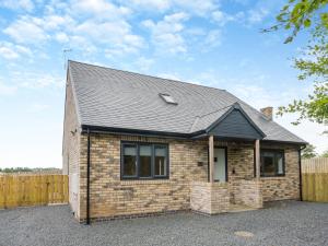 a small brick house with a black roof at The Caddy's Lodge - Uk47762 in Bamburgh +20 photos