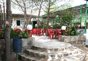 a group of red chairs and tables in a garden at Camping El Canto la Gallina in Valdemaqueda