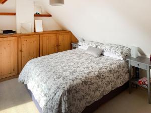 a bedroom with a bed with a gray and white comforter at The Cottage in Whiting Bay