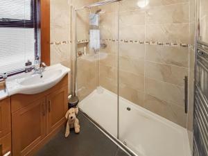 a teddy bear sitting on the floor of a bathroom at The Cottage in Whiting Bay