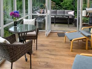 a patio with a glass table and chairs on a porch at The Cottage in Whiting Bay +5 photos