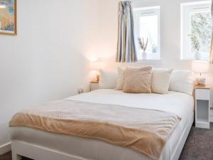 a white bedroom with a bed with white sheets and pillows at Strandside Townhouse in Bude