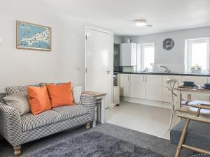 a living room with a couch and a kitchen at Strandside Townhouse in Bude
