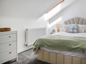 a white bedroom with a bed and a dresser at Strandside Townhouse in Bude +10 photos