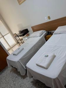 two beds with white sheets in a room with a window at Diplomata Hotel in Sertãozinho