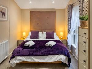 a bedroom with a bed with purple sheets and pillows at Portland in Poole