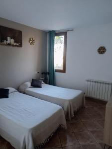 two beds in a room with a window at Masllandrich Hostal Rural in Porqueres