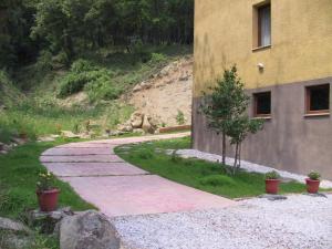 a stone walkway next to a building with a tree at Masllandrich Hostal Rural in Porqueres