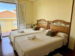 two beds in a room with a large window at Apartamento Albamar 32802 in Pedreña