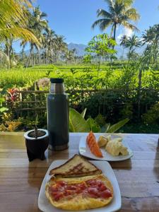 a table with two plates of food and a bottle at Greenfield-Lombok in Tetebatu