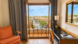 a room with a balcony with a chair and a window at Hotel Monarque Costa Narejos in Los Alcázares +49 photos