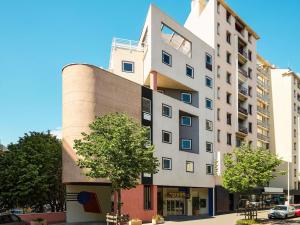 a tall white building with a tree in front of it at greet hotel Marseille Parc Chanot Velodrome by Accor in Marseille
