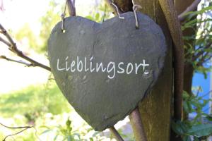 a heart shaped sign hanging on a tree at Paula in Bitz