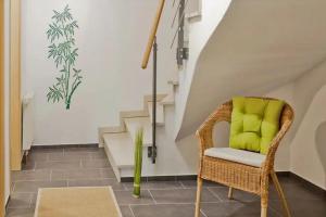 a wicker chair with a green pillow in a room with stairs at Paula in Bitz +7 photos