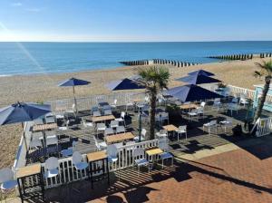 a beach with tables and chairs and umbrellas at West Rocks Hotel in Eastbourne