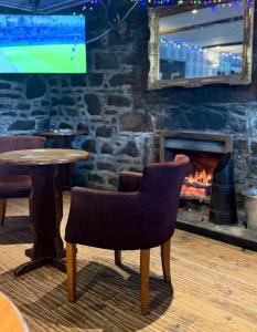 a table and a chair in a bar with a fireplace at Argyll Hotel in Ullapool