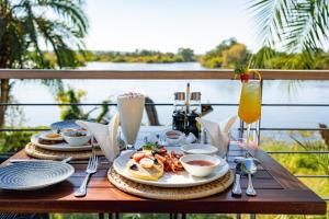 a table with plates of food and drinks on a balcony at The Pods Victoria Falls in Victoria Falls