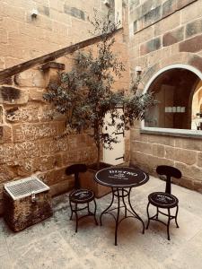 two tables and two chairs in front of a brick wall at Villa La Mola Gozo Luxury Villa with Private Pool & Sunset Views in Għasri