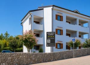 a white building with a sign in front of it at Apartments Kvarner in Malinska