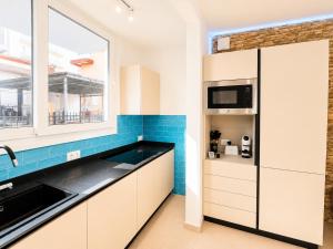 a kitchen with white cabinets and blue tiles at Villa Gaspare in Lido di Jesolo
