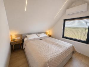 a white bedroom with a bed and a window at Pirtelių resort - Mėlynasis namelis in Kiauleikiai +13 photos