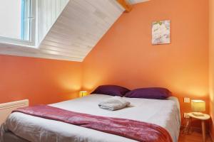 a bedroom with a bed with an orange wall at L'Appartement des Trois Vallées in Villelongue