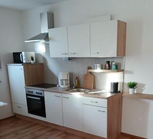 a kitchen with white cabinets and a sink and a stove at Wohlfühloase mit Sauna in Mayen +15 photos
