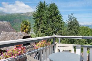a table and a chair on a balcony with flowers at L'Appartement des Trois Vallées in Villelongue